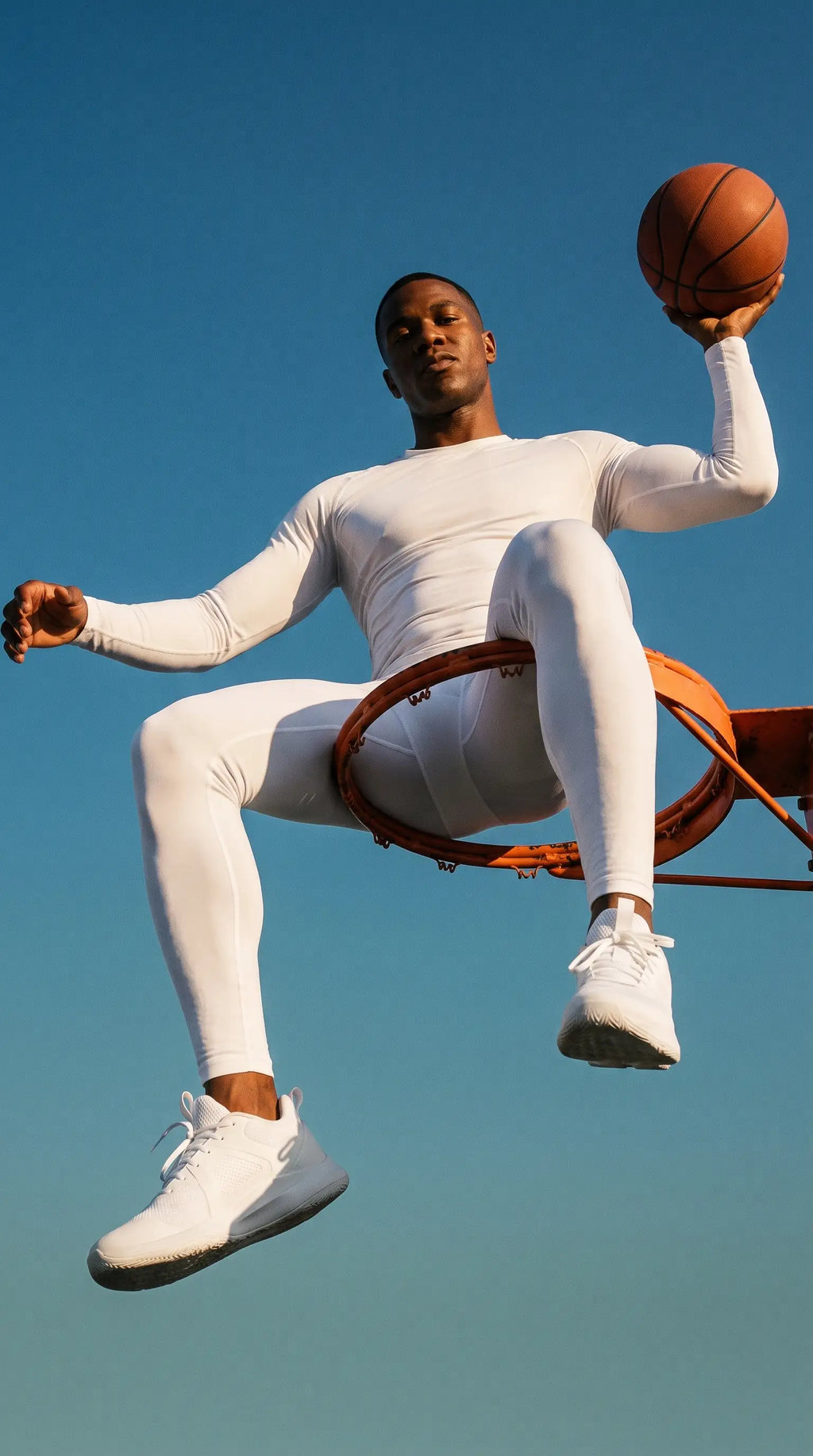 Athlete wearing Men's Recovery Compression Tights while holding a basketball at a hoop against a clear blue sky.