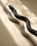 Long dumbbell beam for Pilates in sleek black and beige silicone finishes on a light background.