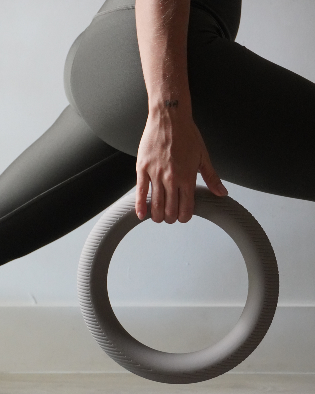 Woman using a ring-shaped dumbbell for home workouts, showcasing ergonomic design and functionality.