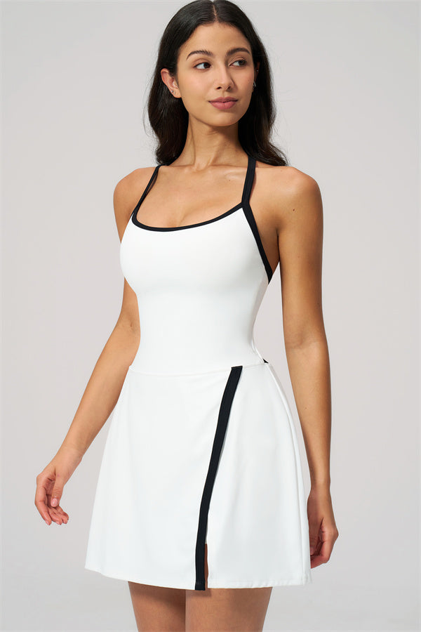 Model wearing The New High End Spunk Tennis Dress in white with black accents, showcasing its stylish and sporty design.