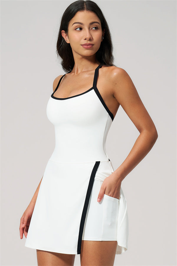 Model wearing The New High End Spunk Tennis Dress in white with black accents, showcasing its stylish design and side pocket.