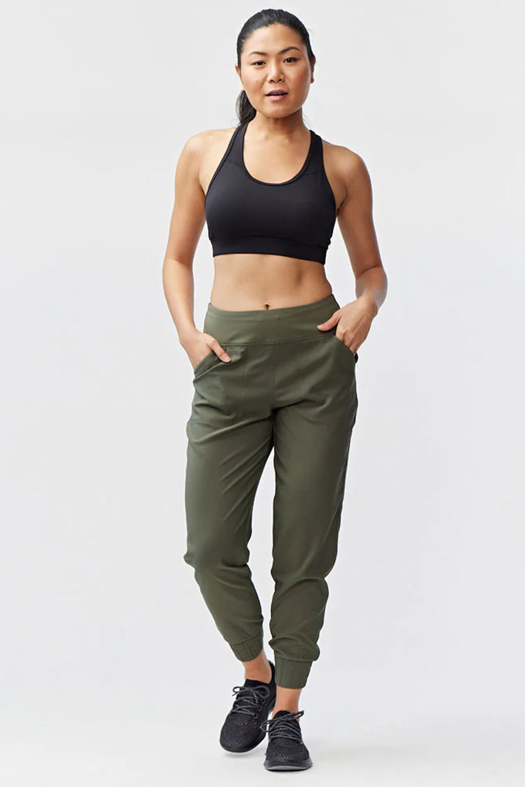 Woman wearing Excel Jogger 78 Length 28 Pant paired with a black sports bra, showcasing a stylish athletic look.