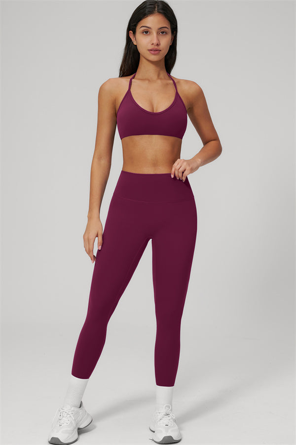 The Rapture Sports Bra Leggings 2-Piece Set model wearing a maroon sports bra and high-waisted leggings while posing.