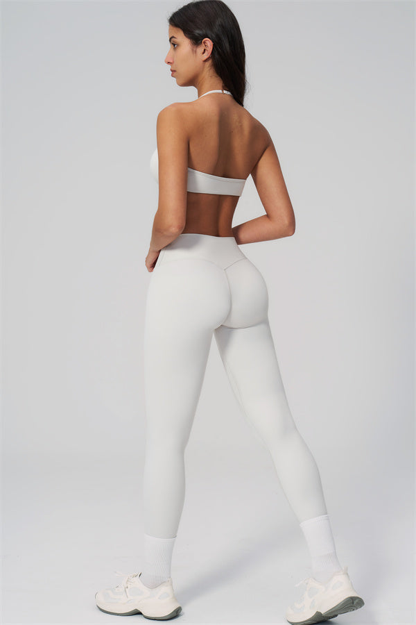The Rapture Sports Bra Leggings 2-Piece Set model wearing white halter sports bra and high-waisted leggings from the back