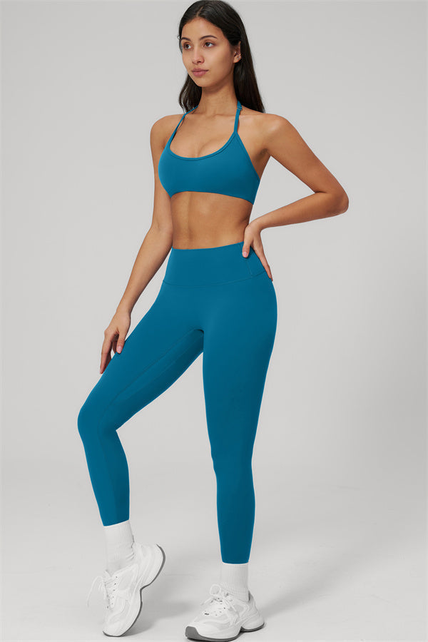 Model wearing The Rapture Sports Bra Leggings 2-Piece Set in teal, showcasing a halter sports bra and high-waisted leggings.