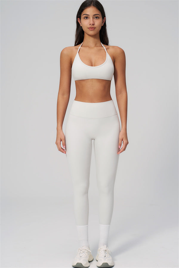 The Rapture Sports Bra Leggings 2-Piece Set modeled in white, showcasing a halter sports bra and high-waisted leggings.